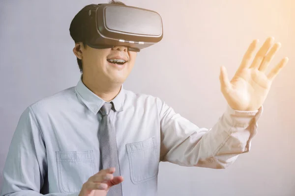 一位泰籍男教师戴着虚拟的现实眼镜 动作有趣而令人兴奋 用手触摸着一个白色背景的模特 — 图库照片