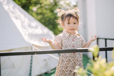 Kızlar gün içinde aileleriyle çadırın önünde koşuşturuyor, eğleniyor ve gülümsüyor.