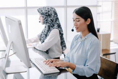 Sekreter danışman yardımı için kulaklık ve mikrofon takar, çağrı merkezi personeli gülümseyen ve mutlu bir şekilde müşterilere tavsiye ve yardım sunar..