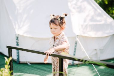 Kızlar gün içinde aileleriyle çadırın önünde koşuşturuyor, eğleniyor ve gülümsüyor.