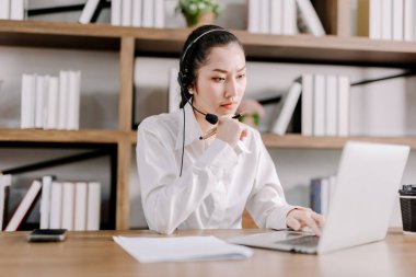 Genç bayan üniversite öğrencileri evlerinden ciddi bir şekilde öğreniyorlar, iş arkadaşlarıyla yoğun bir şekilde çalışmak için video görüşmeleri yapıyorlar, dizüstü bilgisayarlar, kulaklıklar ve not defterleriyle çalışıyorlar..