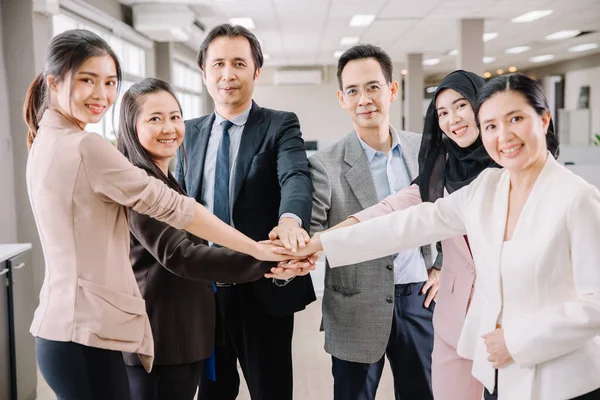 Seçici olarak ellere odaklan. Grup iş adamları, ofiste el ele verip birlik ve güç gösteriyorlar..