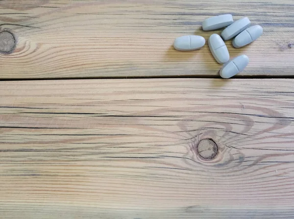 Tabletas grises sobre una mesa de madera. — Foto de Stock