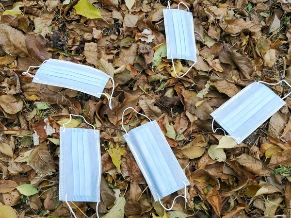 Masques médicaux reposent sur les feuilles tombées. — Photo