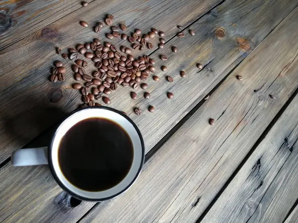 Eine Tasse Americano auf einem Holztisch. Neben den Kaffeebohnen. — Stockfoto