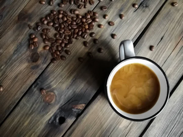 Frisch gebrühter Kaffee mit Milch und Schaum auf einem Holztisch neben den Kaffeebohnen. — Stockfoto