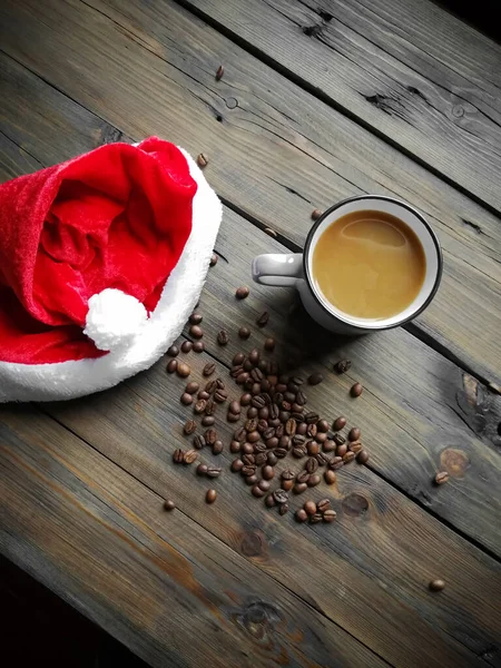 Auf dem Holztisch liegt Kaffee mit Milch, Koi-Bohnen und einer Nikolausmütze. Vertikales Foto. — Stockfoto