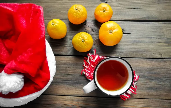 Nikolausmütze, frisch zubereiteter Tee und Manlarins. Winterfeststimmung. Weihnachten und Neujahr. — Stockfoto