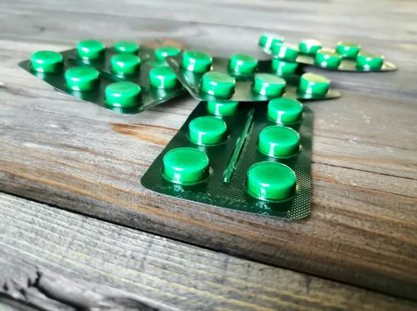 Tablets in green packaging on a wooden table. — Stock Fotó