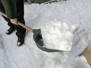 A person removes snow with a shovel for snow. Winter. Snow removal in winter - clean the paths.
