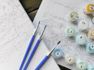 Ressamın fırçaları ve kavanozlardaki parlak renkler resmin üzerine numaralarla ya da rakamlarla boyamak için. Üst görünüm.