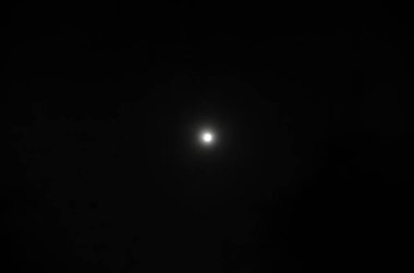 Siyah gökyüzünde beyaz ayın parlak bir noktası var. Beyaz ay, gece karanlığında parlak bir noktadır..