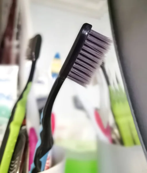 Tandenborstel met zwarte borstels in de badkamer. Reflectie in de spiegel. Gekleurde tandenborstel. Tandenborstel - mondhygiëne. — Stockfoto