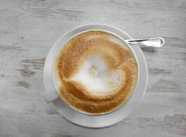 Weiße Tasse mit frisch gebrühtem Cappuccino. Blick von oben auf den Pokal. Köstlicher, üppiger Schaum im Kaffee. Auf Kaffee setzen. — Stockfoto