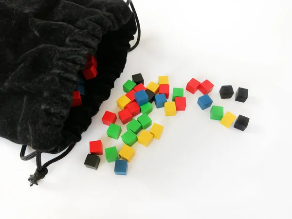 Colored, game cubes next to a black storage bag. Bright cubes for children. Cubes for learning. Game dice.