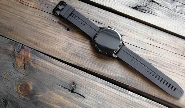 Black smart watch Huawei WATCH GT2 on a wooden table. Black watch on hand. Modern technologies. New model of smart watches.