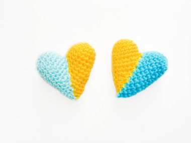 İki kalp, sarı ve mavi yarısıyla tığ işi yapılır. Ukrayna bayrağı. Savaşa hayır. Ukrayna bayrağı gibi sarı-mavi bir kalp. Beyaz arka plan ve kalp. Ellerinle işlediğin bir kalp..