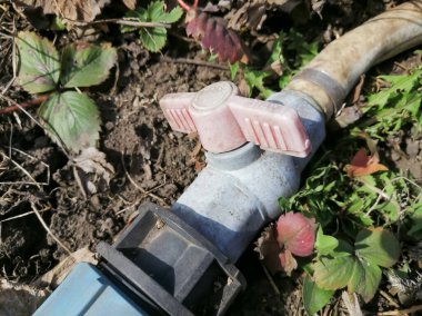 Bahçe hortumuna su sağlamak için girdap. Su kaynağı için musluğu olan eski bahçe hortumu. Hortumdaki su tıkanmış. Su kaynağı yok. Eski valf.