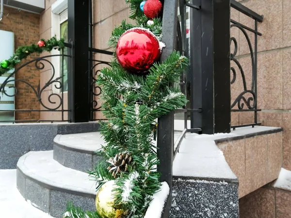 The railings of the staircase are decorated with a Christmas garland with balls and cones. Christmas street decor. — Stock Photo, Image