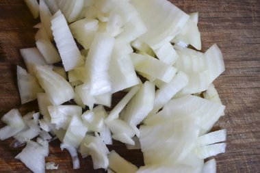 Tahtada doğranmış soğan. Doğranmış soğan. Yay küpleri tahtada. Tabağın içeriği. Soğan.