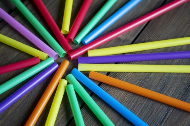 İçmek için birçok renkli pipet ahşap bir masada yatar. Bir tüp çemberi. Masanın üzerinde plastik pipetler var. Kokteyller için plastik pipetlerin soyutlanması.