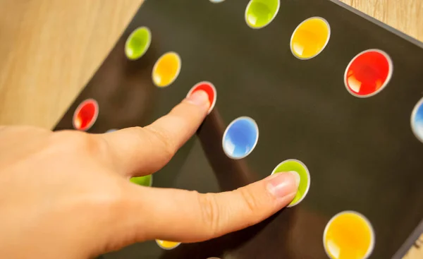 A hand-held twister game. twister on your fingers. a person\'s fingers on two colored circles.