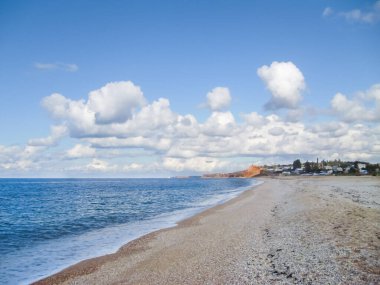 Okyanus kıyısında. Deniz kenarındaki güzel kumlu sahil. Denizin yanındaki Shiirk kumsalında. Kumsalda bulutlu gökyüzü.