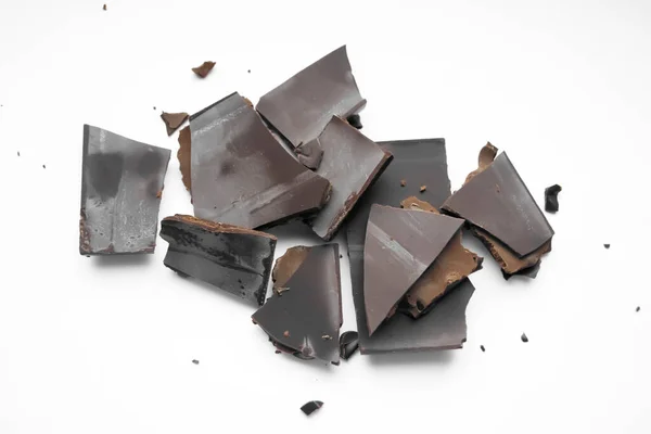 Pieces of broken chocolate on the table. On a white background, pieces of chocolate lie on a slide.