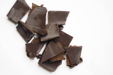 Masanın üzerinde kırık çikolata parçaları var. Beyaz arka planda, çikolata parçaları bir kaydırağın üzerinde yatıyor..