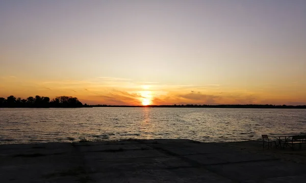 A bright sunset over the lake. orange sunset over the water. The sky sets over the horizon orange sky.