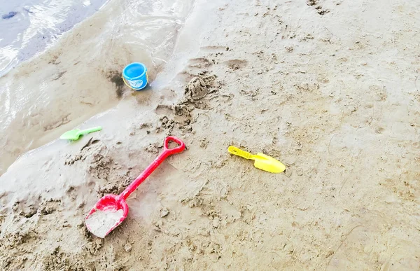 Children\'s toys on the beach. Scattered on the sand are the child\'s toys for pasoks. Blades and buckets for sculpting pastes on the sand.