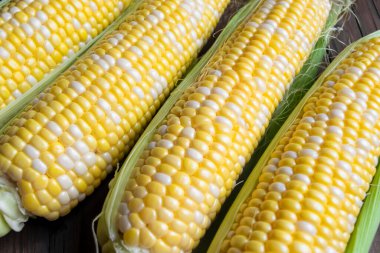 Yellow-white corn of the Raquel variety. corn ears are lying on a wooden table. Colored corn on the table.