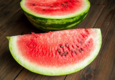 On a wooden table are slices of watermelon. Watermelon quarters on a wooden base. Watermelon season, big. sweet berries.