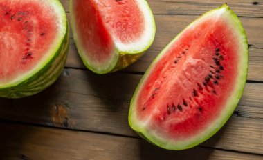 On a wooden table are slices of watermelon. Watermelon quarters on a wooden base. Watermelon season, big. sweet berries.