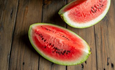 Watermelon quarters on a wooden table. Two slices of sweet, red watermelon on a brown tree.