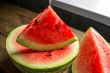 Watermelon cut into small triangles on a wooden board. On a wooden table is a board with slices of watermelon. Sweet slices of watermelon with bones.