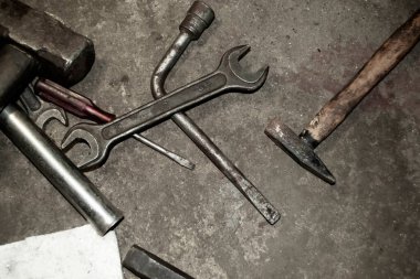 Scattered tools. There is a wrench on the concrete floor. hammer and other tools. On concrete is a dirty working tool.