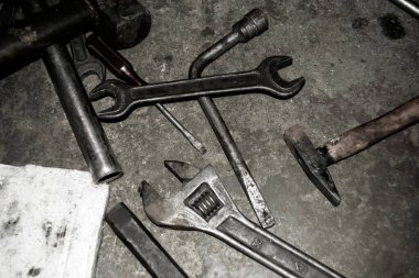 Scattered tools. There is a wrench on the concrete floor. hammer and other tools. Black and white photo. On concrete is a dirty working tool.