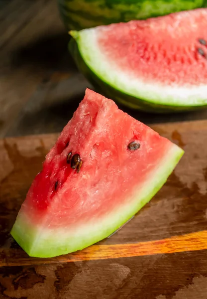Sweet watermelon with pits on a wooden table. A triangular slice of watermelon on a wooden table. beautiful slice of watermelon.