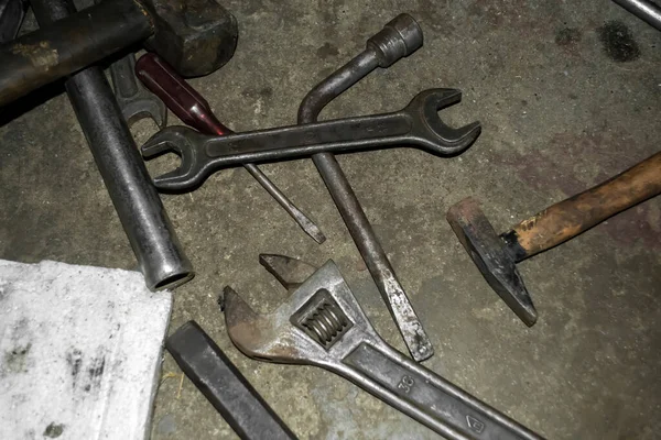 Scattered tools. There is a wrench on the concrete floor. hammer and other tools. On concrete is a dirty working tool.