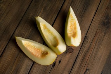Only melons on a wooden table. On the table are three slices of melon. Ripe melon on a wooden background.