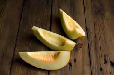 Only melons on a wooden table. On the table are three slices of melon. Ripe melon on a wooden background.