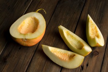 Melon lunch is vegetarian. On a wooden table lies half a melon and three slices. peeled melon, without seeds on the table.