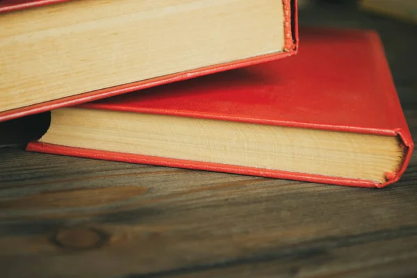 Two red books on a wooden table. Macro photography of two books with red covers. Wooden background and books with scarlet covers.