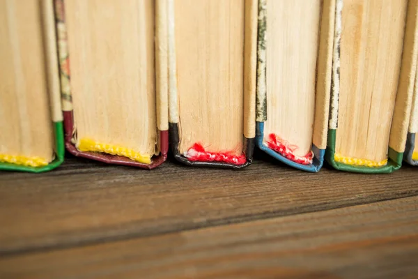 Books with colored spine stand on a wooden table. The stubs of books on a wooden background. Color books. A number of old literature.