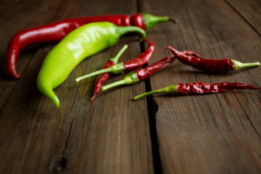 different types of hot peppers on the table. Chilli pepper on a table of different types. Small red hot peppers and chilli green and red on a wooden background.