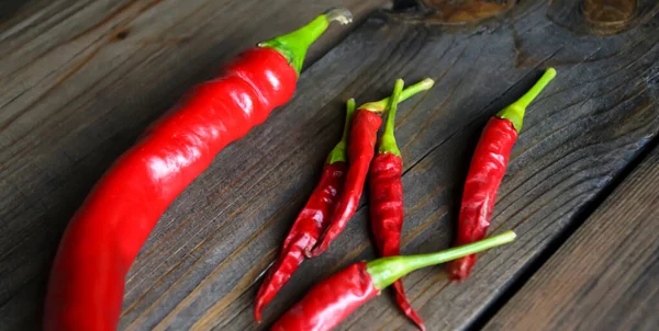 Lots of different chili peppers on the table. Red hot peppers. Red hot pepper, different types. two kinds of hot peppers on a wooden table.