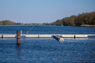 Kürek yarışmaları için suda bariyerler ve işaretlerle dolu bir nehir.