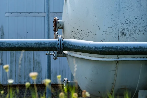 Closeup Metal Pipe Tank Blurred Flowers Foreground — 图库照片