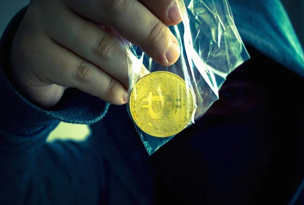 Kapüşonlu kimliği belirsiz biri yüzünü kapattı ve şeffaf bir çanta dolusu bitcoin para uzattı.
